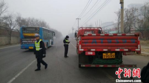 資料圖：2015年12月8日下午，京開高速路輔路大莊橋路段，環(huán)境監(jiān)察人員檢查路上行駛的大貨車。張尼 攝