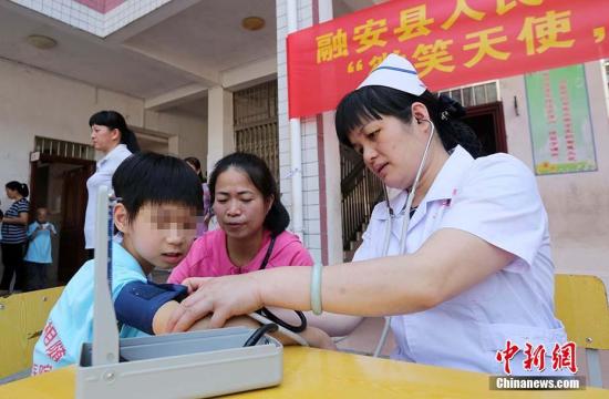 資料圖：5月10日，在廣西柳州市融安縣特殊教育學(xué)校，一名醫(yī)護(hù)人員在為學(xué)生量血壓。 譚凱興 攝